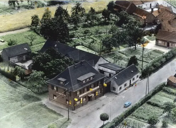 Historische, kolorierte Luftaufnahme des Anwesens Manes am Bösch mit Feldern und Gärten