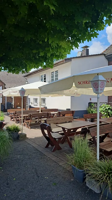 Terrasse mit Holzbänken und Sonnenschirmen vor dem Manes am Bösch