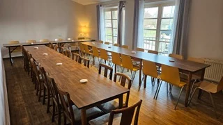 Gastraum im Obergeschoss mit warmem Holzboden, eingedeckt für eine Feier